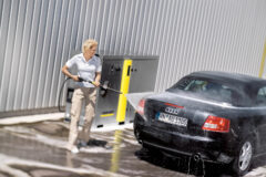 kobieta myje myjką ciśnieniową Karcher czarny samochód na jednostanowiskowej myjni samoobsługowej